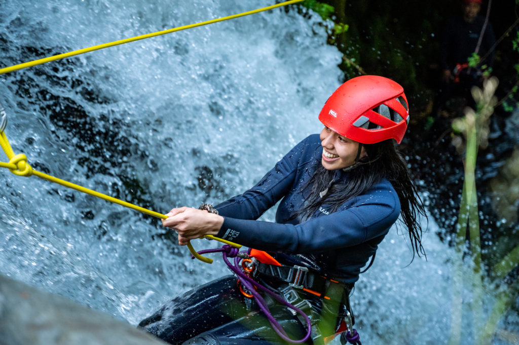 Canyoning en el Rio Correntoso de Pucón. Turista rapeleando la cascada con cuerda.