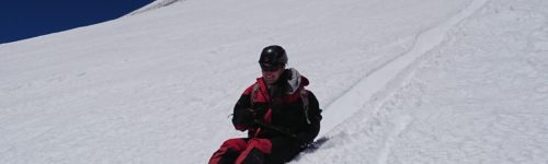 Persona deslizando sentada en la nieve