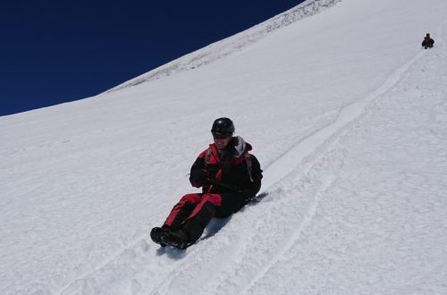 Persona deslizando sentada en la nieve