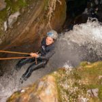 Persona haciendo rappel en una cascada de agua