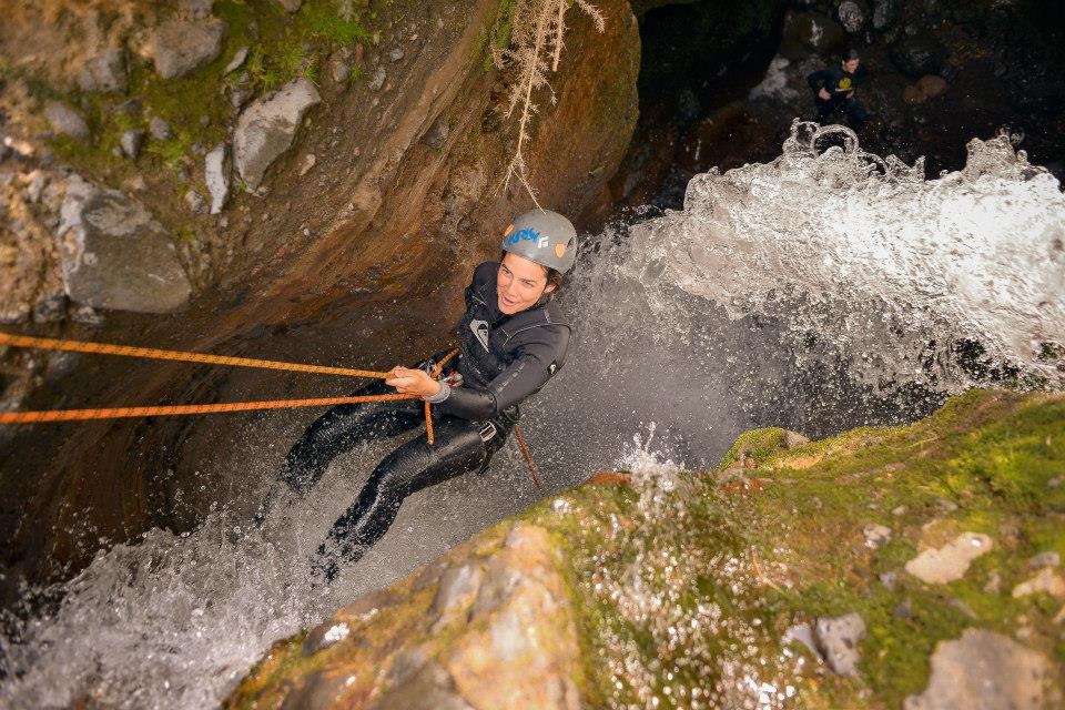 Persona haciendo rappel en una cascada de agua